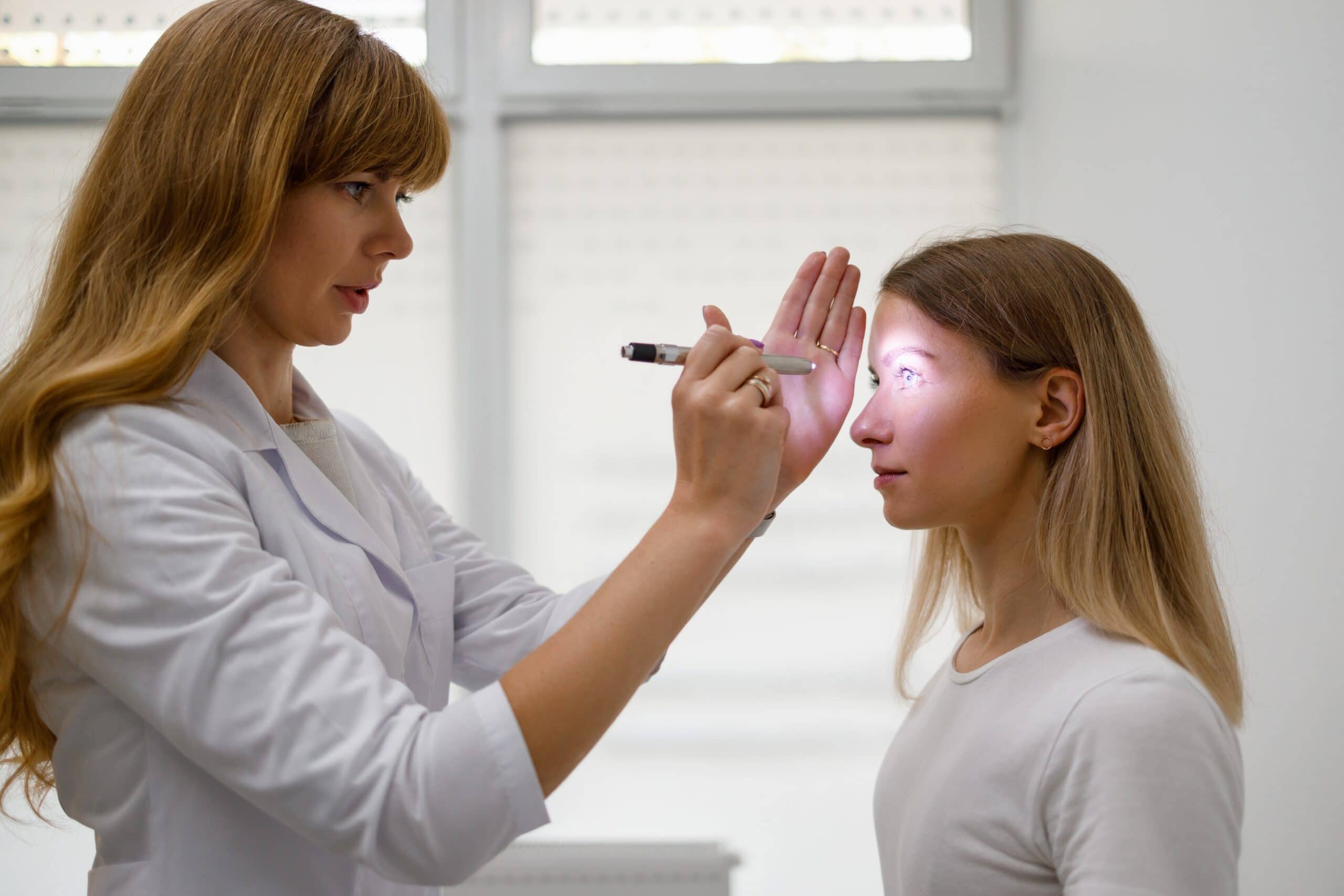 female,doctor,checking,young,female,patient's,eyes,with,fashlight.,diagnosis