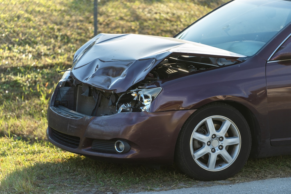 crashed,and,dented,car,parked,along,a,residential,street,near