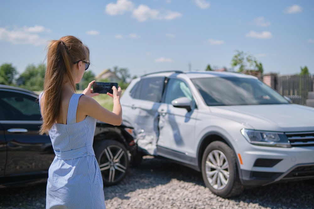 stressed,driver,taking,picture,on,sellphone,camera,of,smashed,vehicle