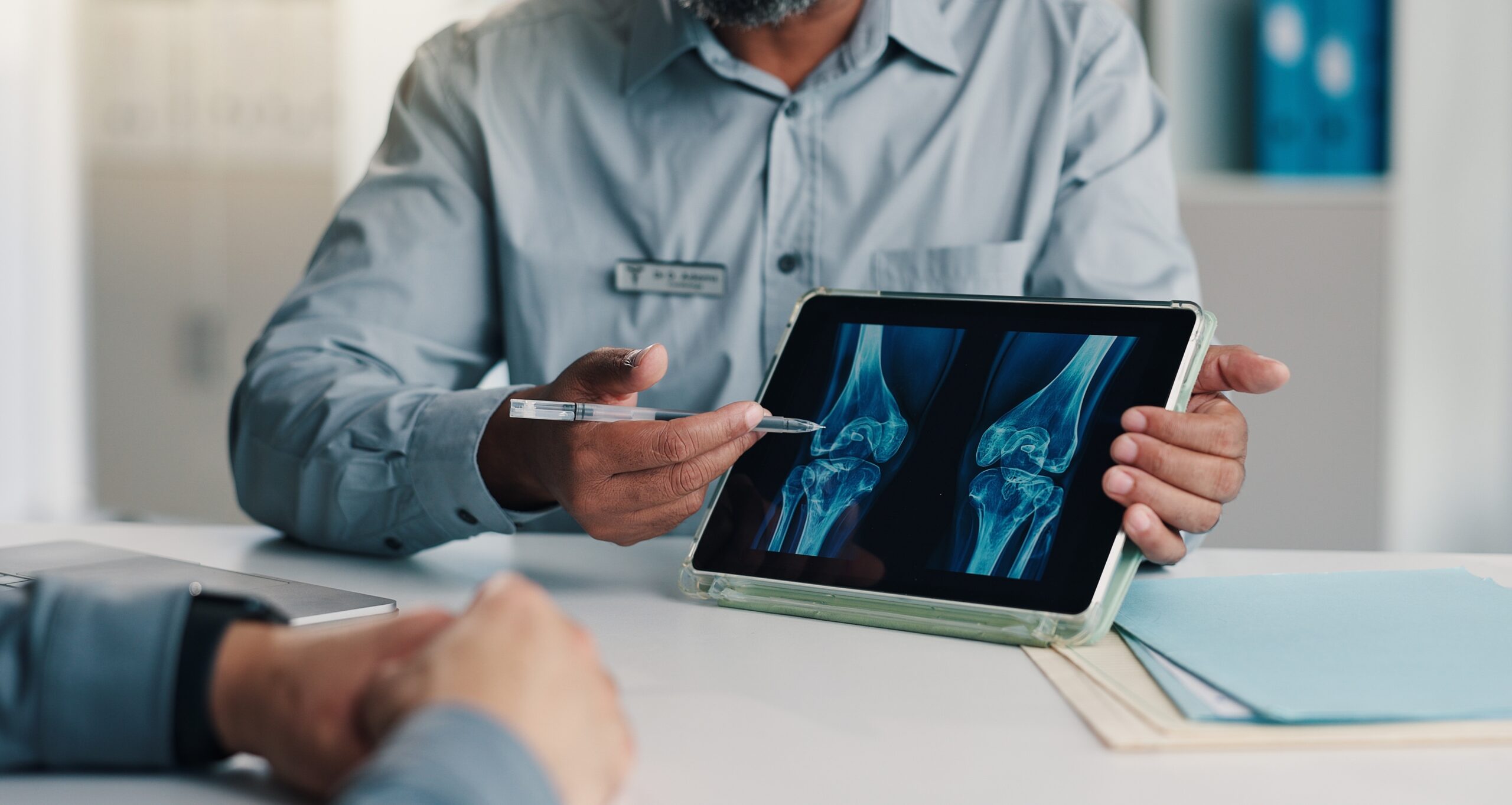 doctor pointing at tablet showing xray image of patients knee